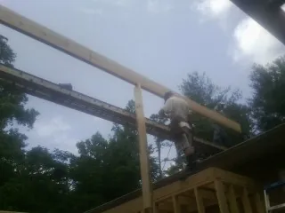Carpenter setting a ridge beam over a new addition frame — Ice Dam Removal by Roofing Brothers in Petersburg