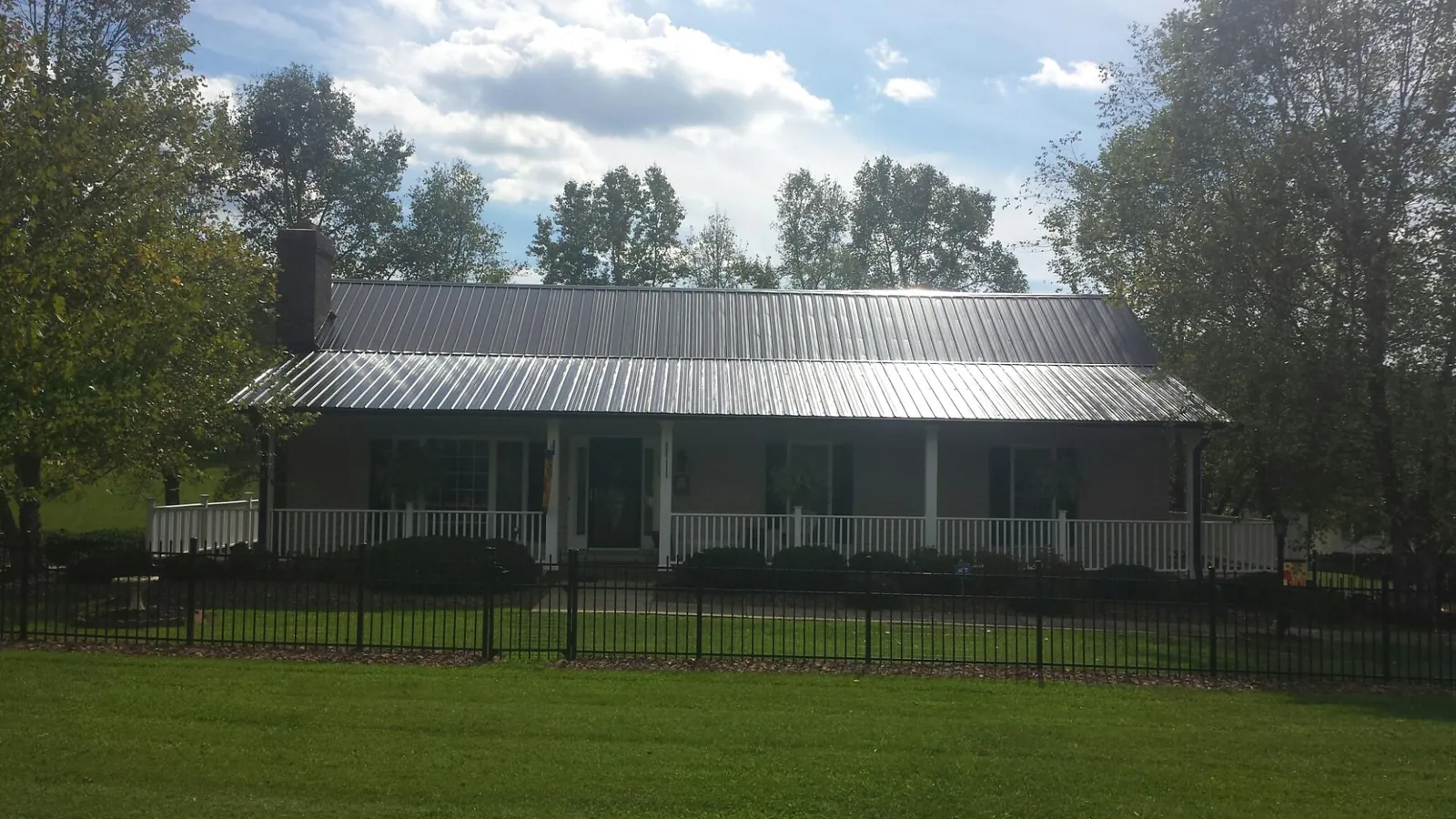 Gray metal roof on a brick ranch with a full width front porch — Gutter Guard Installation work by our crew in Petersburg